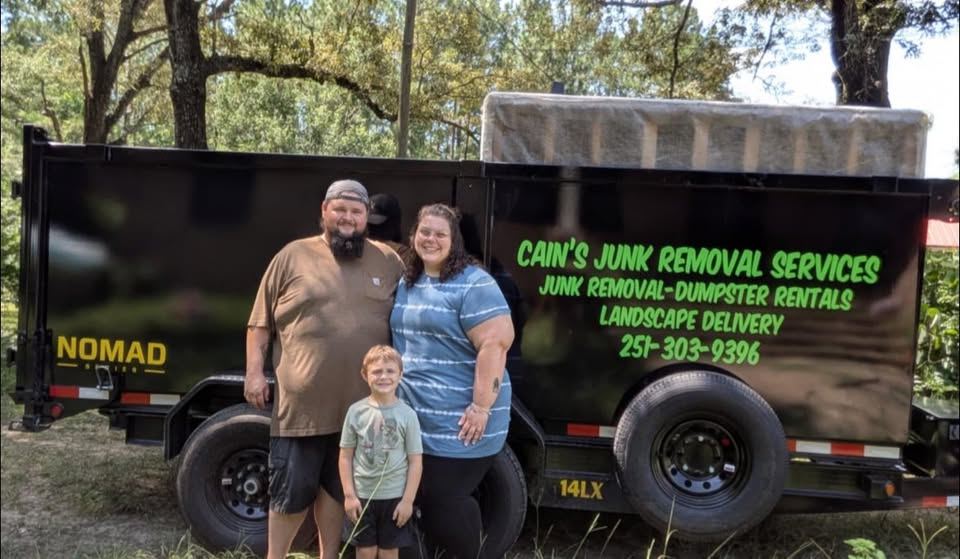 Cowen and Cassidy Cain with their son, standing in front of the black Cain's Junk Removal dump trailer.